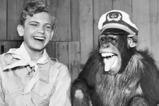 A boy and a chimpanzee seemingly laughing together