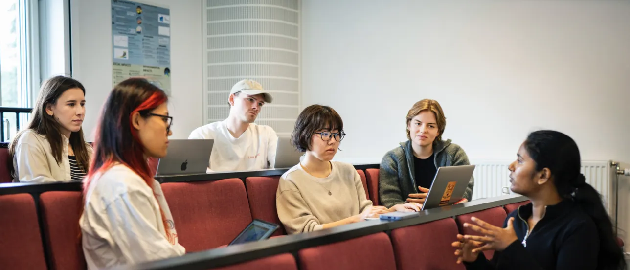 Students engaging in conversation in a classroom. Photo.