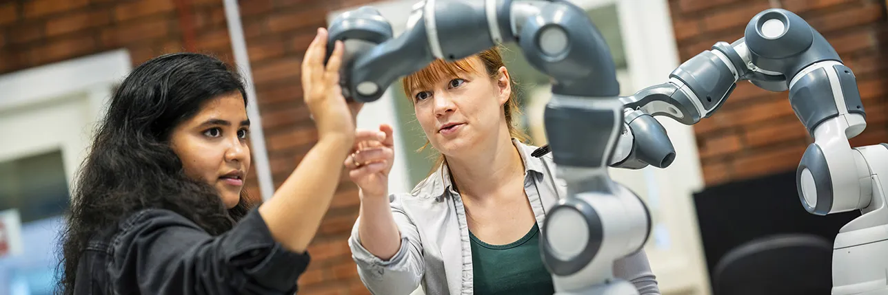 Two people working with a robotic arm in a laboratory. Photo.