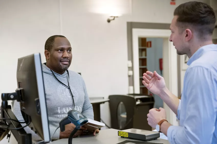 Library staff explaining something to a doctoral student