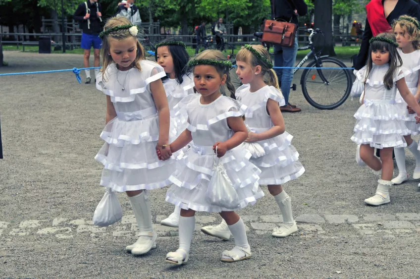 Wreath bearers in white dresses holding hands
